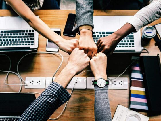 Software developers fist bumping each other over laptops and mobile devices