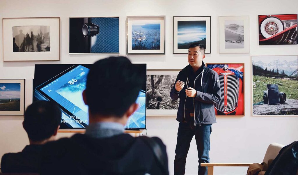 Product Owner leading a meeting with a mobile application on a tv screen