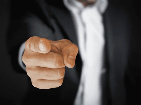 Picture of a man in a work suit pointing at the reader