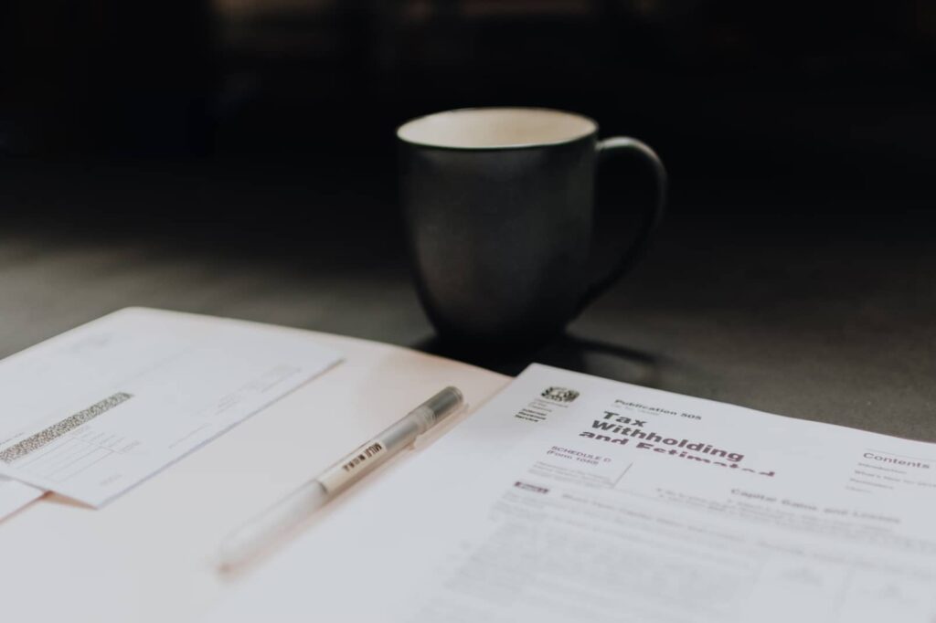 An open packet on a desk with tax information inside, next to a cup of coffee.