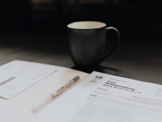 An open packet on a desk with tax information inside, next to a cup of coffee.