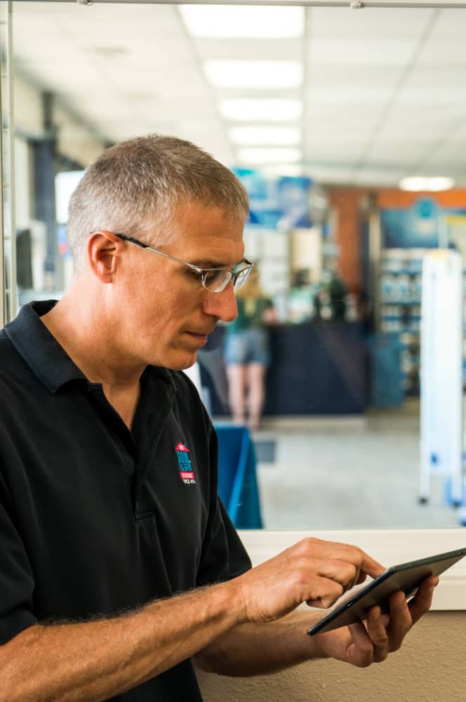 man working in pool store using evosus software on ipad