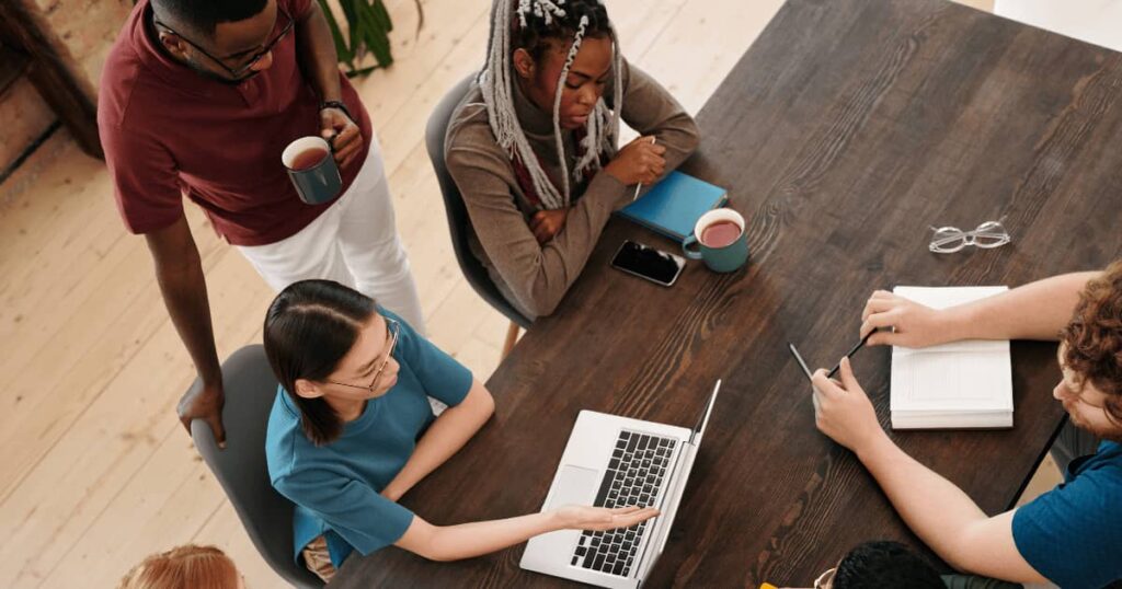 coworkers sitting at a table in a meeting discussing something